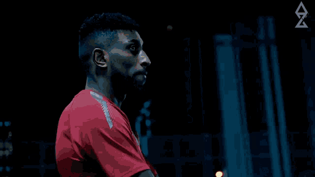 a man in a red shirt is standing in a dark room with an arrow pointing to the right