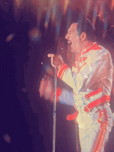 a man is singing into a microphone with a crowd behind him