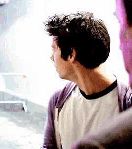 a man wearing a white shirt and a purple jacket looks to the side