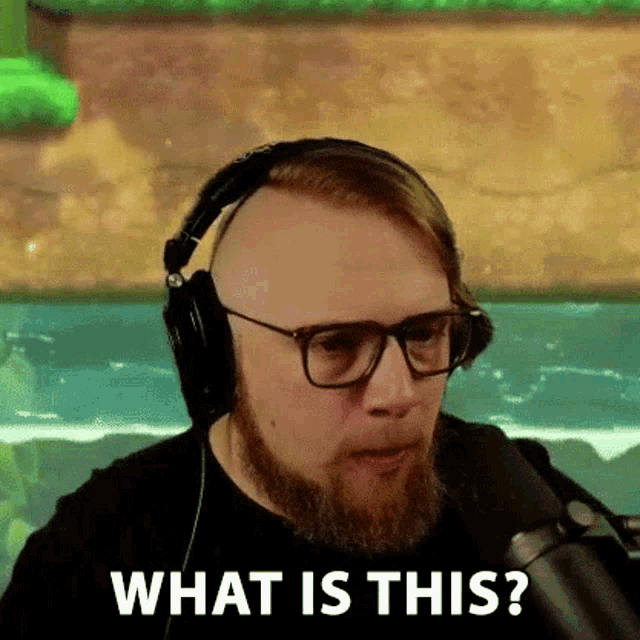 a bald man with a beard and glasses is wearing headphones and a microphone .