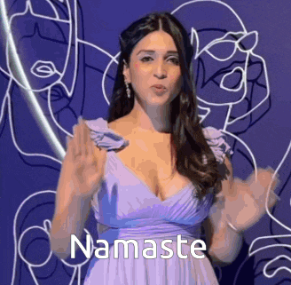 a woman in a purple dress is saying namaste with her hands in the air