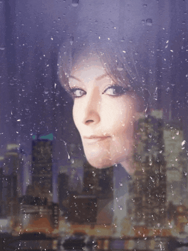 a woman looking out a window with rain drops on the glass