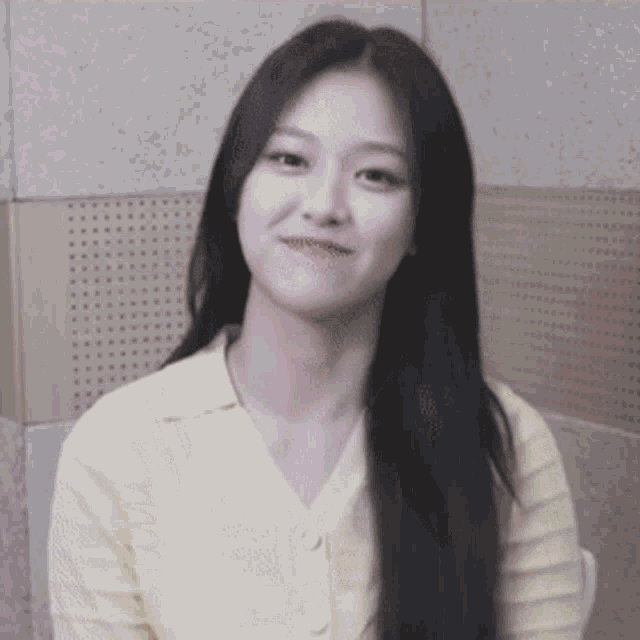 a woman with long black hair wearing a yellow shirt