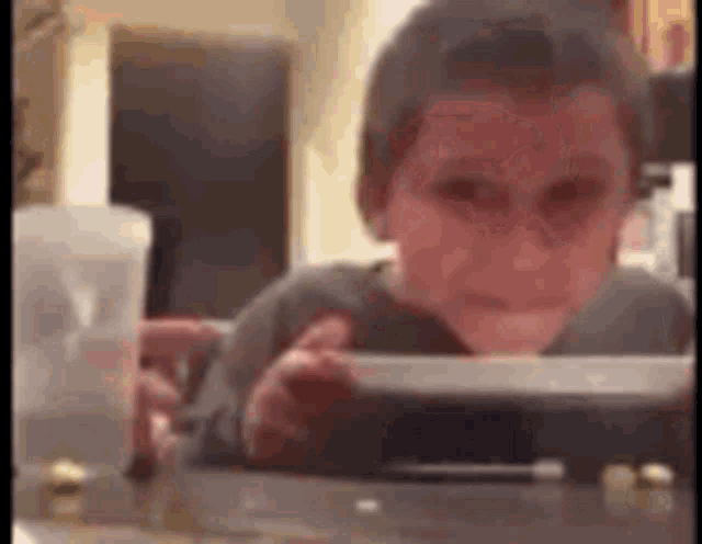 a young boy is sitting at a table looking at a tablet computer .