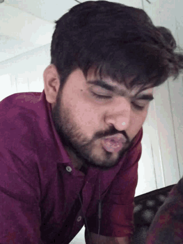 a man with a beard wearing a purple shirt is sleeping with his eyes closed