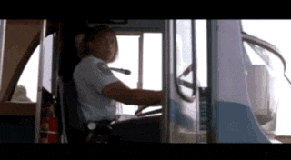 a woman is driving a bus with a fire extinguisher in front of her
