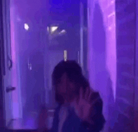 a blurry picture of a woman dancing in a purple room .
