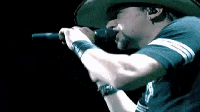 a man singing into a microphone with a cowboy hat