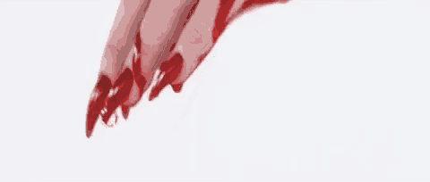 a close up of a woman 's hand with long red nails covered in red nail polish .