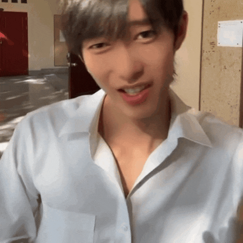 a man in a white shirt is smiling and looking at the camera