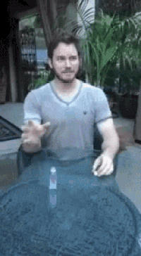 a man with a beard is sitting at a table with his hands outstretched .