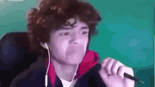 a young man with curly hair is wearing headphones and crying while smoking a cigarette .