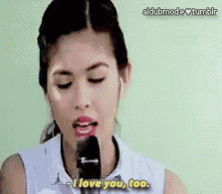 a woman is singing into a microphone and saying i love you too