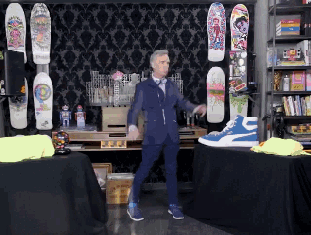 a man in a suit is dancing in front of a wall of skateboards including one that says ' a '