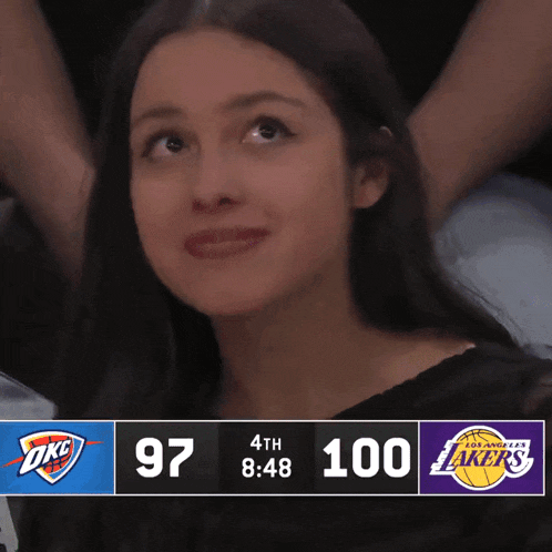 a woman watches a basketball game between the okc and lakers