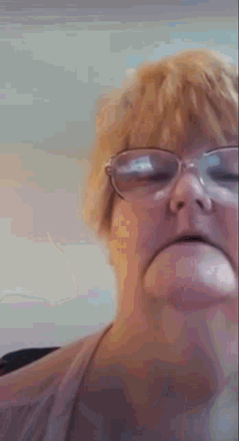 a woman wearing glasses is making a funny face .