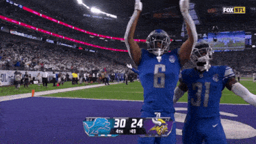 two football players celebrate on the field with a scoreboard that says 30 24