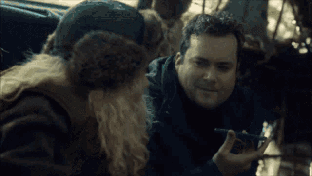 a man in a fur hat talks to another man in a car
