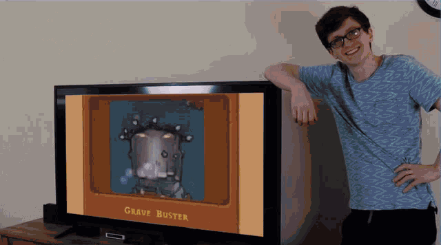 a man stands in front of a large flat screen tv that says grave buster on the screen