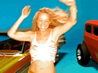a woman in a white tank top is dancing in front of a red car