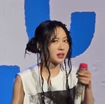 a woman in a white tank top is holding a pink microphone .
