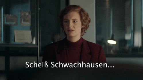 a woman in a red jacket stands in front of a sign that says scheiß schwanhausen