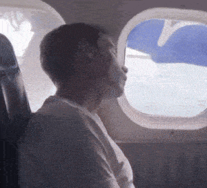 a man sits in a plane looking out the window at the ocean