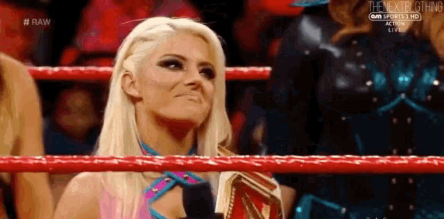 a woman is sitting in a wrestling ring holding a championship .