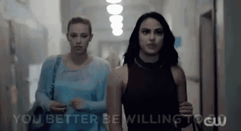 two women are walking down a hallway with the words `` you better be willing to '' written on the wall .