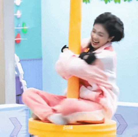 a woman is sitting on top of a yellow carousel and smiling .