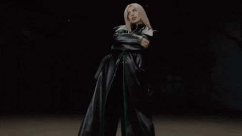 a woman in a black and green outfit is standing in the dark .