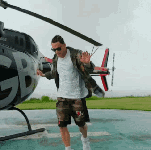 a man standing in front of a helicopter with the letter gb on it