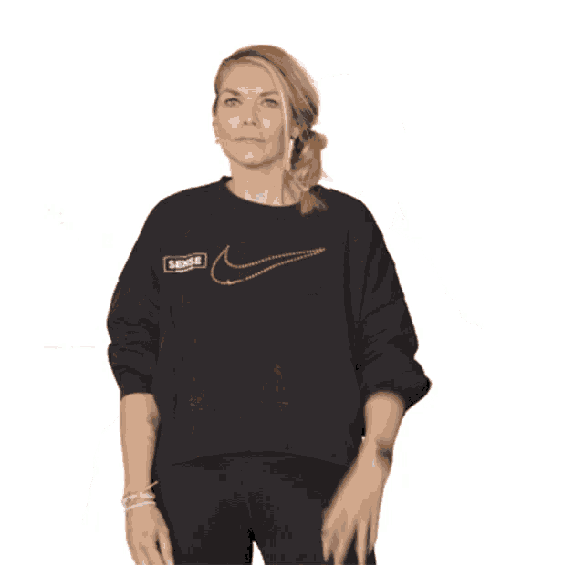 a woman is wearing a black nike sweatshirt and black pants