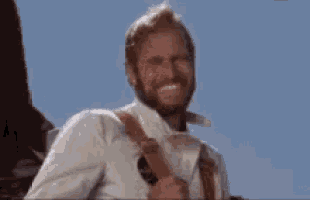 a man with a beard is smiling while holding a gun .