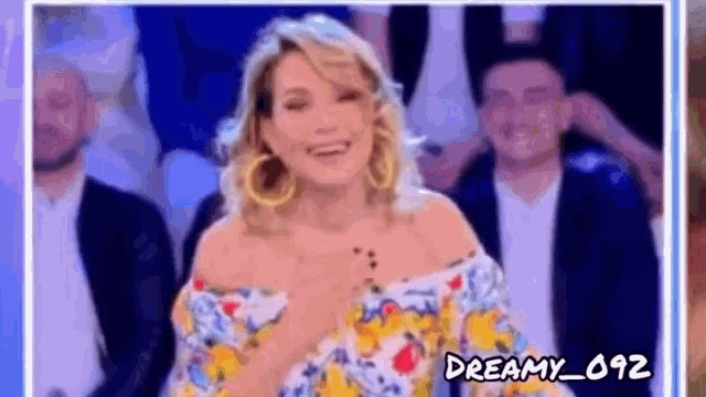 a woman in a floral dress is smiling while standing in front of a crowd .