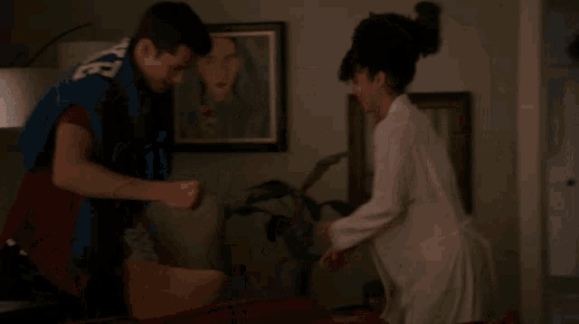 a man and a woman are dancing in a living room with a picture on the wall behind them