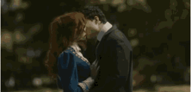 a man and a woman are kissing in the park .