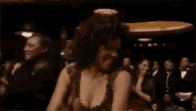 a woman in a dress is dancing in front of a crowd of people in a dark room .