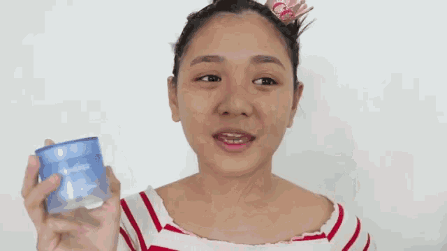 a woman in a red and white striped shirt is holding a jar of laneige moisturizing cream .
