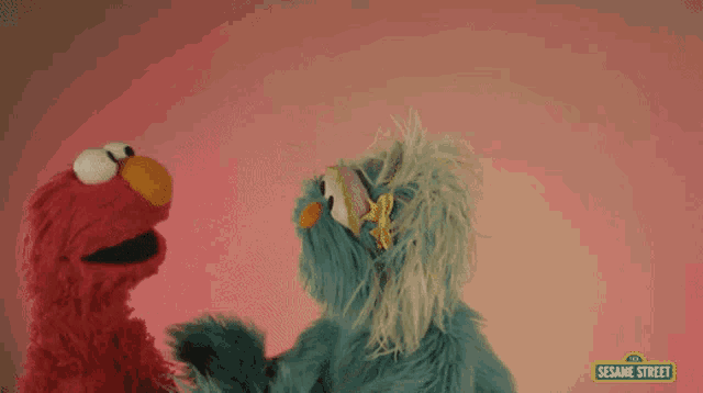 two sesame street characters are hugging each other on a pink background