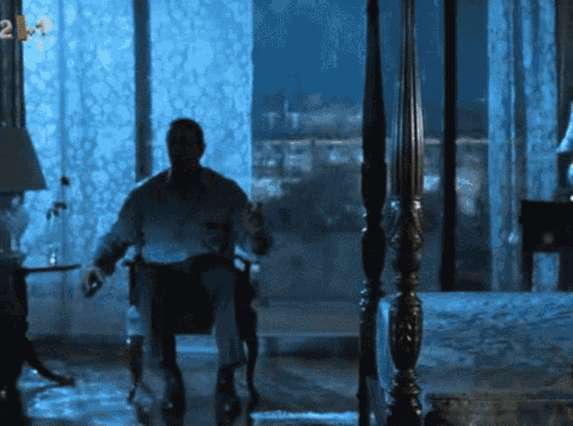 a man sits in a chair in front of a window with the number 2 on the bottom