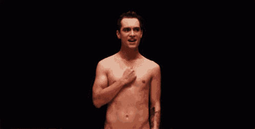 a shirtless man with a tattoo on his arm is standing in front of a black background .