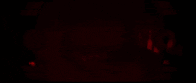 a person is standing in a dark room with a red light shining on them .