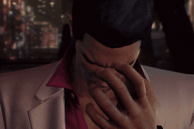 a man in a white suit with a pink collar is covering his face with his hand