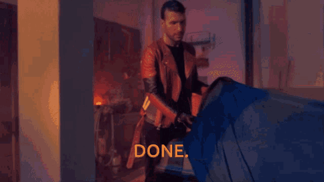 a man in a leather jacket is holding a piece of cloth that says done on it