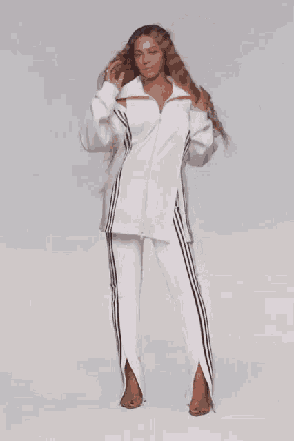 a woman wearing a white shirt and white pants with black stripes