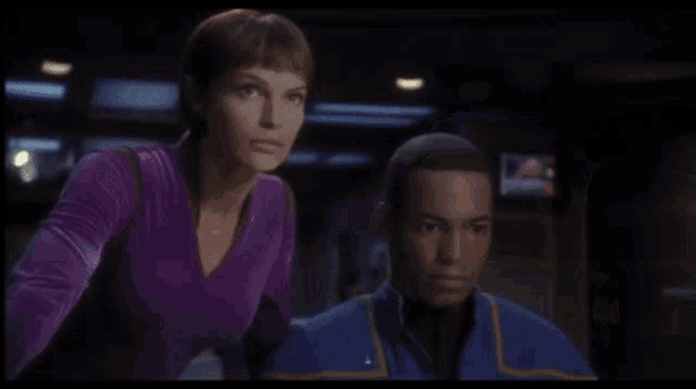 a man and a woman standing next to each other in a dark room