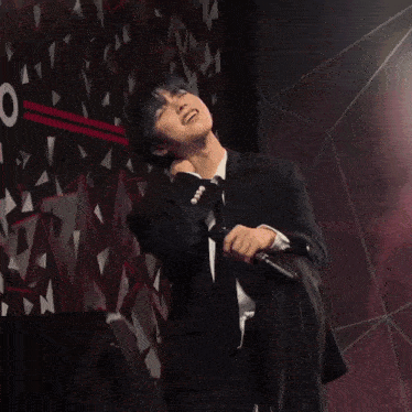 a man in a black suit is dancing on stage