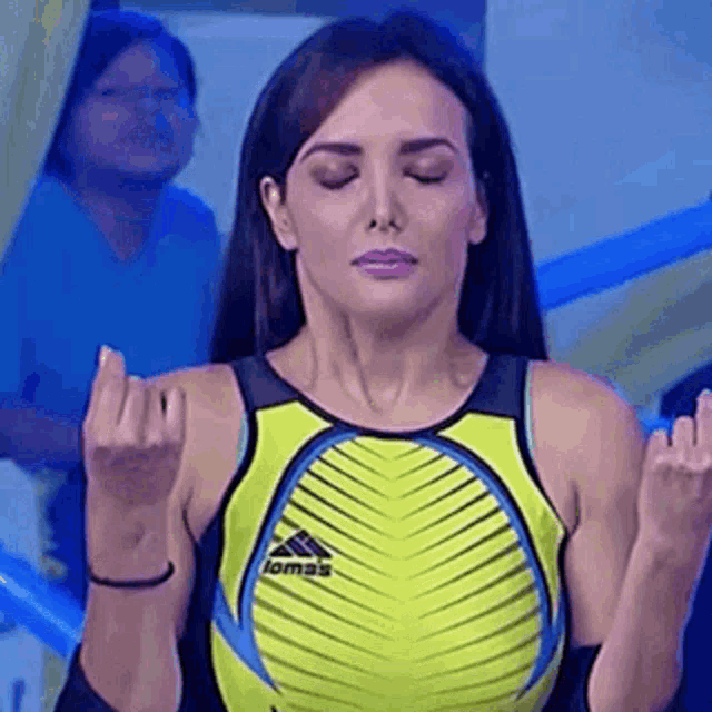 a woman in a yellow tank top is making a middle finger gesture .
