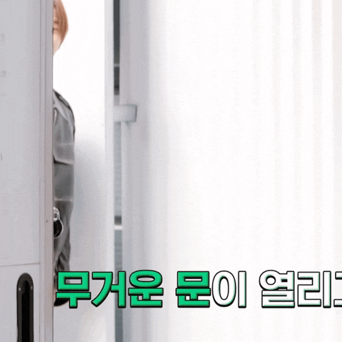 a person peeking out from behind a door with korean writing
